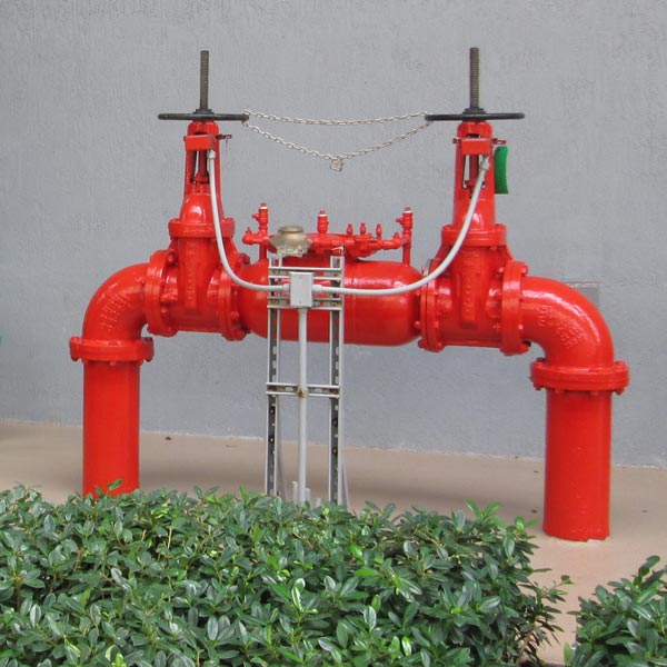 Backflow preventer assembly with control valves installed against a gray wall